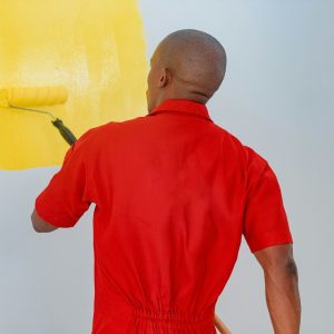 a man painting a wall with yellow paint